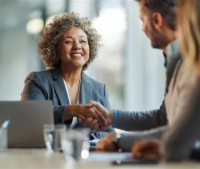 Business woman shaking hands with client at meeting table