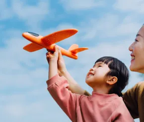 A mother helps her daughter play with a toy plane