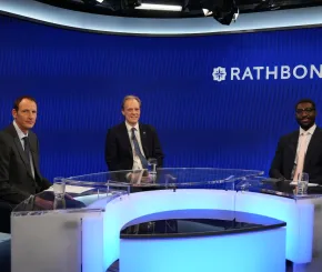 Three males sitting at a table in front of the Rathbones logo