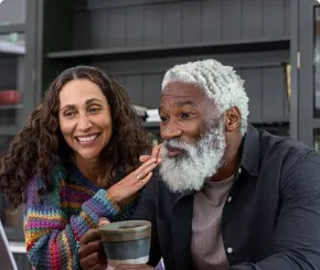 A retired couple smile while they have a video call on their laptop