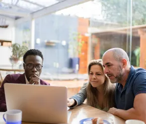 Financial adviser showing clients data on laptop while sitting in their conservatory