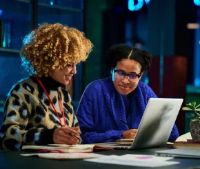 Two female colleagues working on laptops