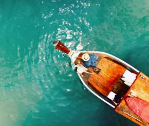 Aerial view of a traditional wooden boat on clear turquoise water.