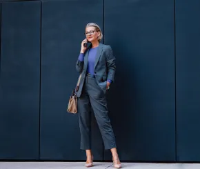 Professional business woman standing on phone infront of navy blocked wall