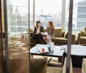 Two women sitting on sofa reviewing documents
