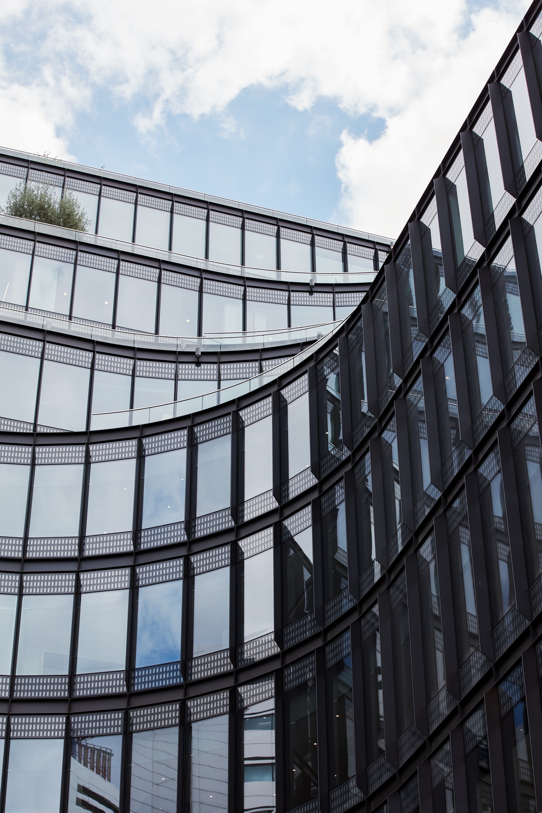 Looking up towards the glass face of a corporate office building with blue sky in the background