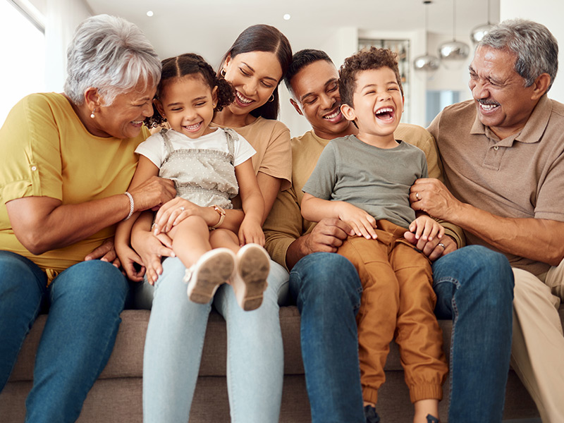 multi-generational family together on a sofa laughing and smiling