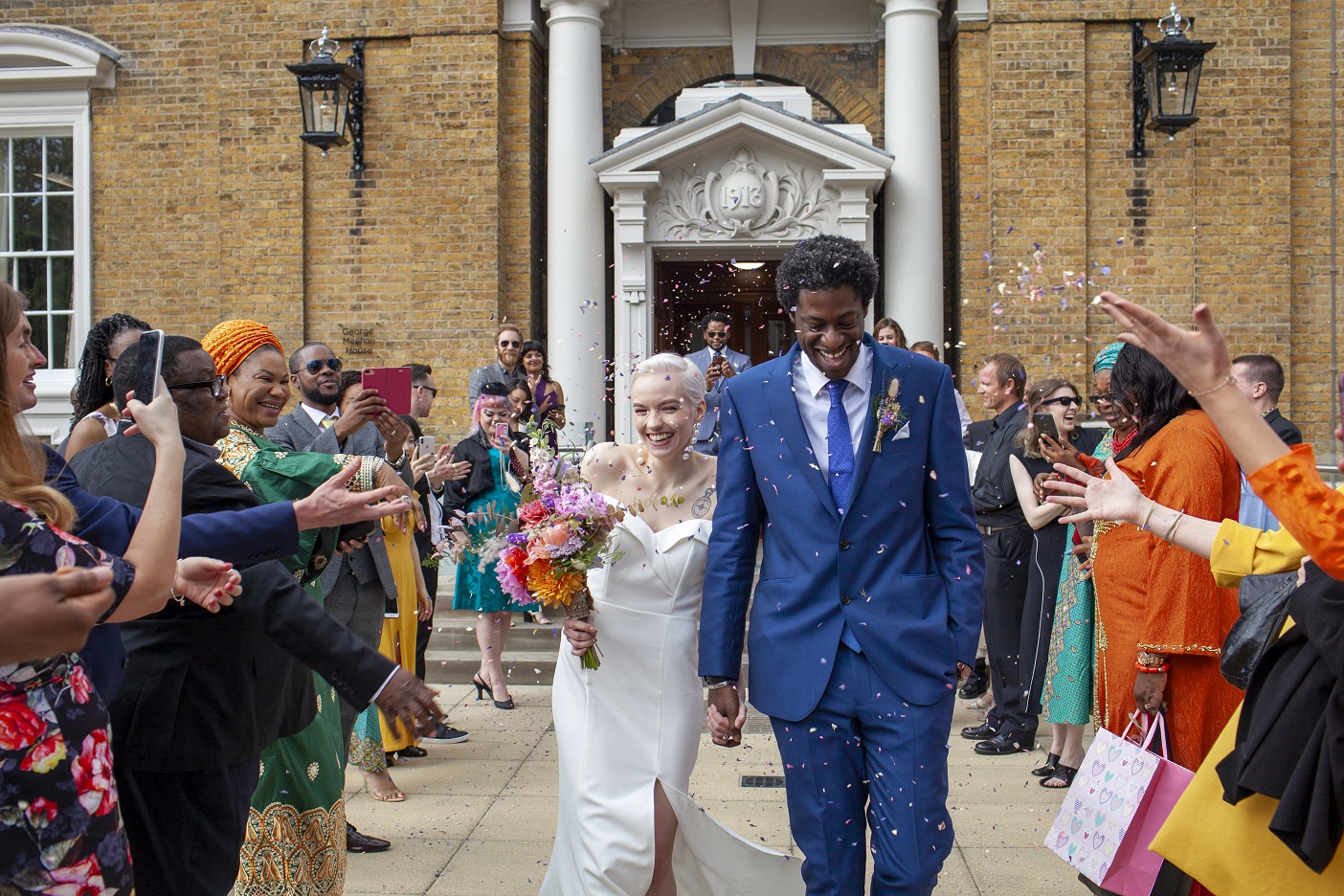 Newlyweds walk out of their town hall to a crowd throwing rice and flowers at them