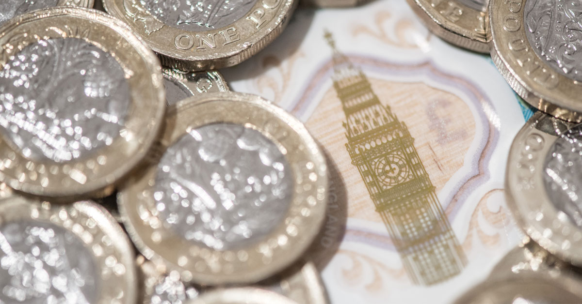 pound coins piles on top of each other with a note behind with Big Ben central