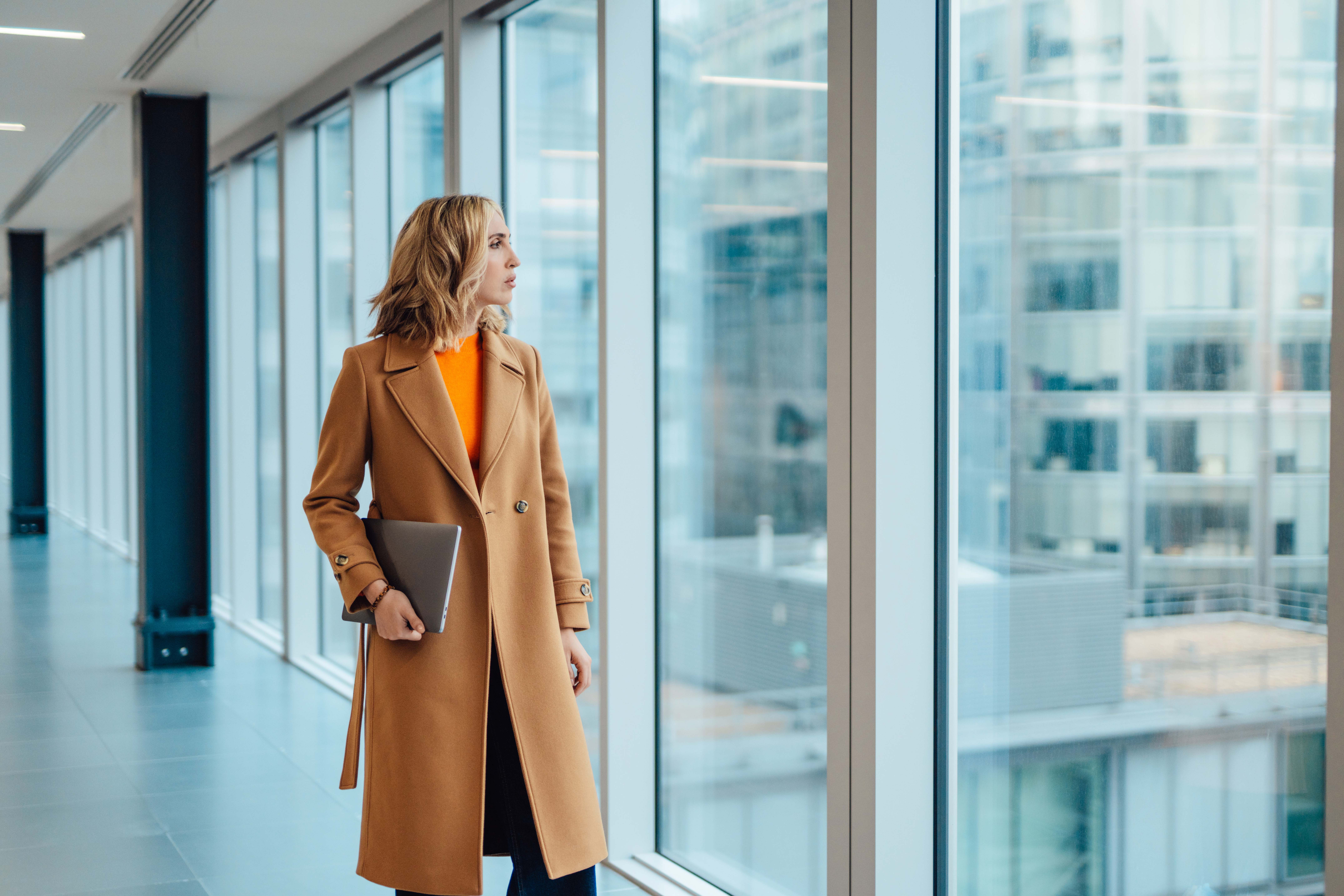 A lady walks along a corridor of a glass walled office